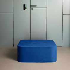 a blue ottoman sitting in front of some white cabinets