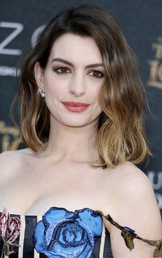 a woman in a strapless dress with flowers on her chest and shoulder, posing for the camera