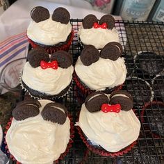 several cupcakes with white frosting and mickey mouse ears on them sitting on a cooling rack