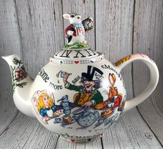 a ceramic teapot with an image of alice and the neverland pirates on it