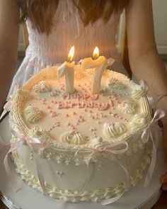 a girl holding a birthday cake with two lit candles