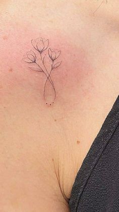 a woman's chest with a single flower tattoo on her left side ribcage