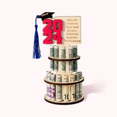 a stack of twenty dollar bills with a graduation cap on top and the number twenty twenty dollars