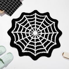 a black and white spider web rug next to slippers