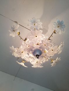 a chandelier with white flowers hanging from it's ceiling fixture in a room