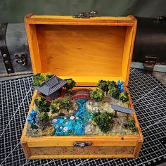 an open wooden box filled with miniature houses and trees