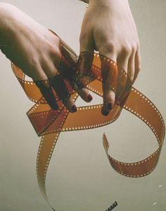 two hands holding a film strip in the air with water around them and an object floating on top of it