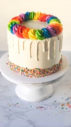 a white cake with rainbow icing and sprinkles on the top layer