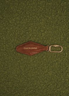 a wooden keychain with the word california on it is laying on green carpet