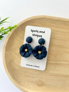 the blue flower earrings are sitting on top of a wooden table next to a potted plant