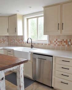 a kitchen with white cabinets and a wooden table in front of the dishwasher