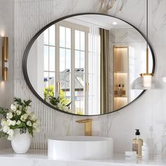 a bathroom with a large round mirror above the sink and flowers in vases on the counter