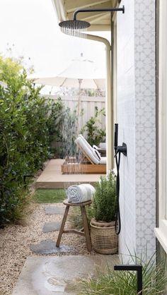 an outdoor shower is shown in the back yard with potted plants on the side