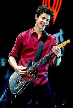 a young man playing an electric guitar on stage