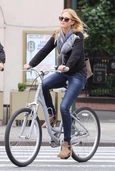 the woman is riding her bike down the street with another person in the back seat