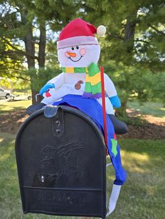 a stuffed snowman sitting on top of a mailbox