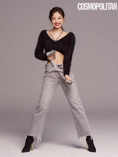 a woman in black top and grey jeans posing for a magazine cover with her hands on her hips