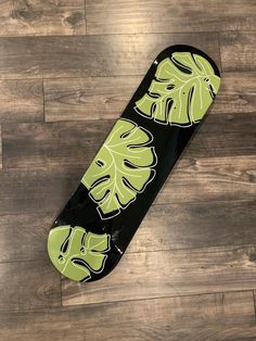 a skateboard with green leaves on it laying on a wooden floor