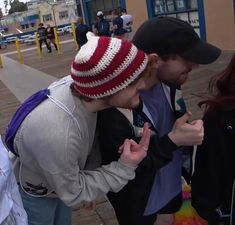 two people standing next to each other with their fingers in the air and one person wearing a hat