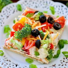 a white plate topped with a piece of pizza covered in veggies and cheese