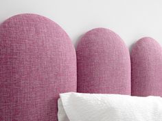 a pink headboard with white sheets and pillows