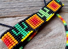 a multicolored beaded necklace on a wooden surface with beads in the shape of an arrow