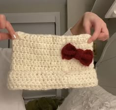 someone is holding up a crocheted purse with a red bow on the front