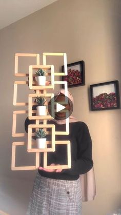 a woman standing in front of a wall holding up a planter made out of blocks