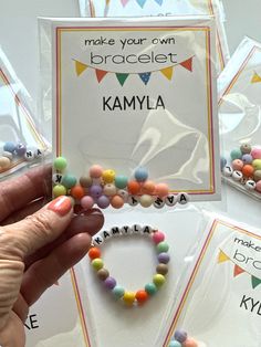 a person holding up a card with beads on it and the words make your own bracelet