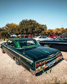 an old green car parked in a parking lot