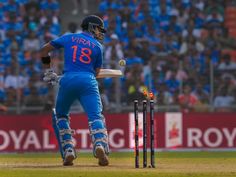a man in blue uniform playing a game of cricket with people watching from the stands