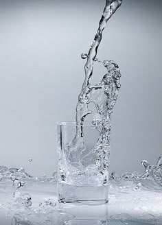 water pouring into a glass with ice cubes on the bottom and splashing around