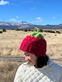 a woman wearing a red knitted strawberry hat