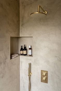 a bathroom with a gold faucet, shower head and soap dispenser