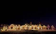 a large house with christmas lights on it's windows and trees in the front yard