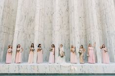 a group of women standing next to each other in front of a wall with columns