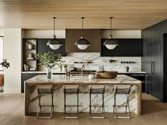 a large kitchen with marble counter tops and stools in front of the center island