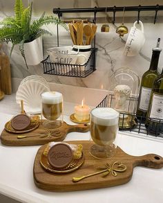 two wooden trays filled with drinks on top of a counter next to bottles and candles