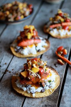 several small pizzas with different toppings on top of them sitting on a wooden table