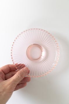 a person is holding a clear glass bowl in their left hand on a white surface