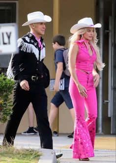 a man and woman in cowboy hats walking down the street