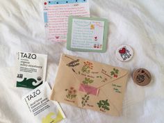 an envelope and some other items on a bed with white sheets, buttons and magnets