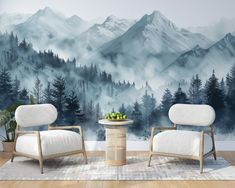 two chairs and a table in front of a wall with a mountain scene painted on it