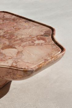 a marble topped table on top of a white floor with a brown wooden frame around the edge