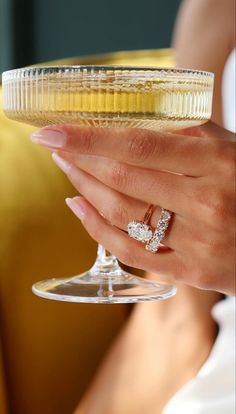 a close up of a person holding a wine glass with a diamond ring on it