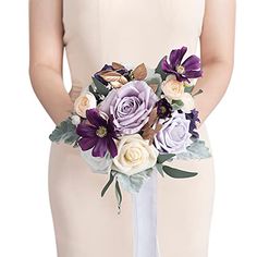 a woman wearing a white dress holding a purple and white flower bouquet in her hand