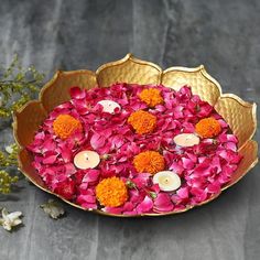 a bowl filled with flowers and candles on top of a table