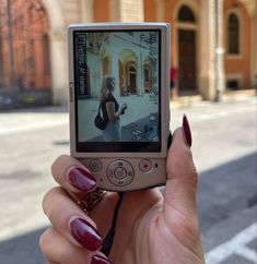 a woman is holding up her cell phone to take a selfie in the street