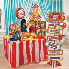 two children sitting at a table with carnival signs