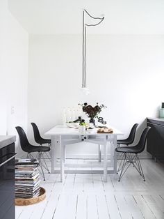 a white table with black chairs in a small room next to an oven and microwave